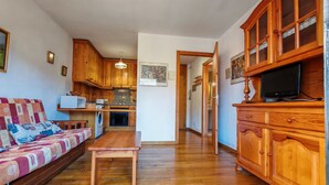 Ein Wohnzimmer mit einer Couch, einem Holztisch und einer Küchenzeile mit Holzausstattung und einer Mikrowelle.