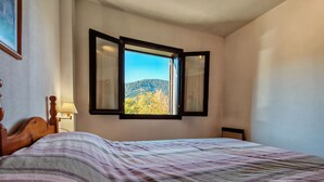 Ein Schlafzimmer mit einem Bett, einem Fenster mit Bergblick und einer Lampe auf dem Nachttisch.