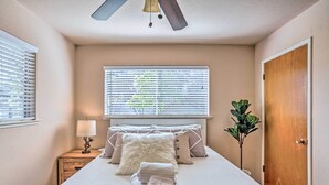 A neatly made bed with a fluffy pillow, a bedside lamp, and a folded towel on a wooden nightstand. - Lovely Oakhurst Cabin w/ Deck & Mtn Views! (Oakhurst)