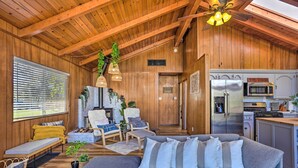 A cozy cabin interior with a wooden ceiling, a gray sofa, a fireplace, and a kitchen area. - Lovely Oakhurst Cabin w/ Deck & Mtn Views! (Oakhurst)