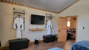 A room with two beds, a TV, a wooden ceiling, and a door leading to a living area. - Private Retreat with Pond, Pool and Hot Tub (Boyd)