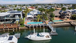 Un port de plaisance avec des bateaux amarrés, une piscine et des maisons modernes équipées de panneaux solaires.