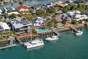 Un port de plaisance où sont amarrés de nombreux bateaux, une piscine et des immeubles résidentiels équipés de panneaux solaires.