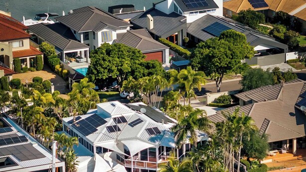 Un port de plaisance où sont amarrés plusieurs yachts, une piscine et des immeubles résidentiels équipés de panneaux solaires.