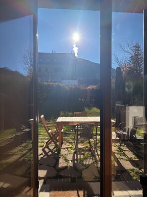 A patio with a table and chairs, a view of a mountain, and a building in the background.