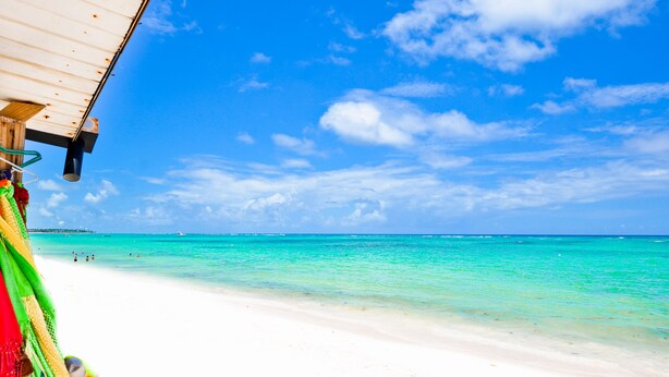 Een strand met helder turquoise water en een witte zandkust.