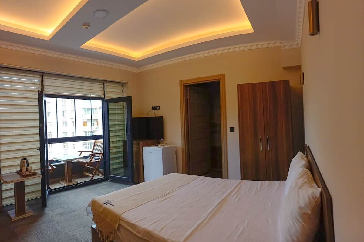 Ein Schlafzimmer mit Bett, Fernseher, Kleiderschrank und einer Glastür zu einem Balkon.
