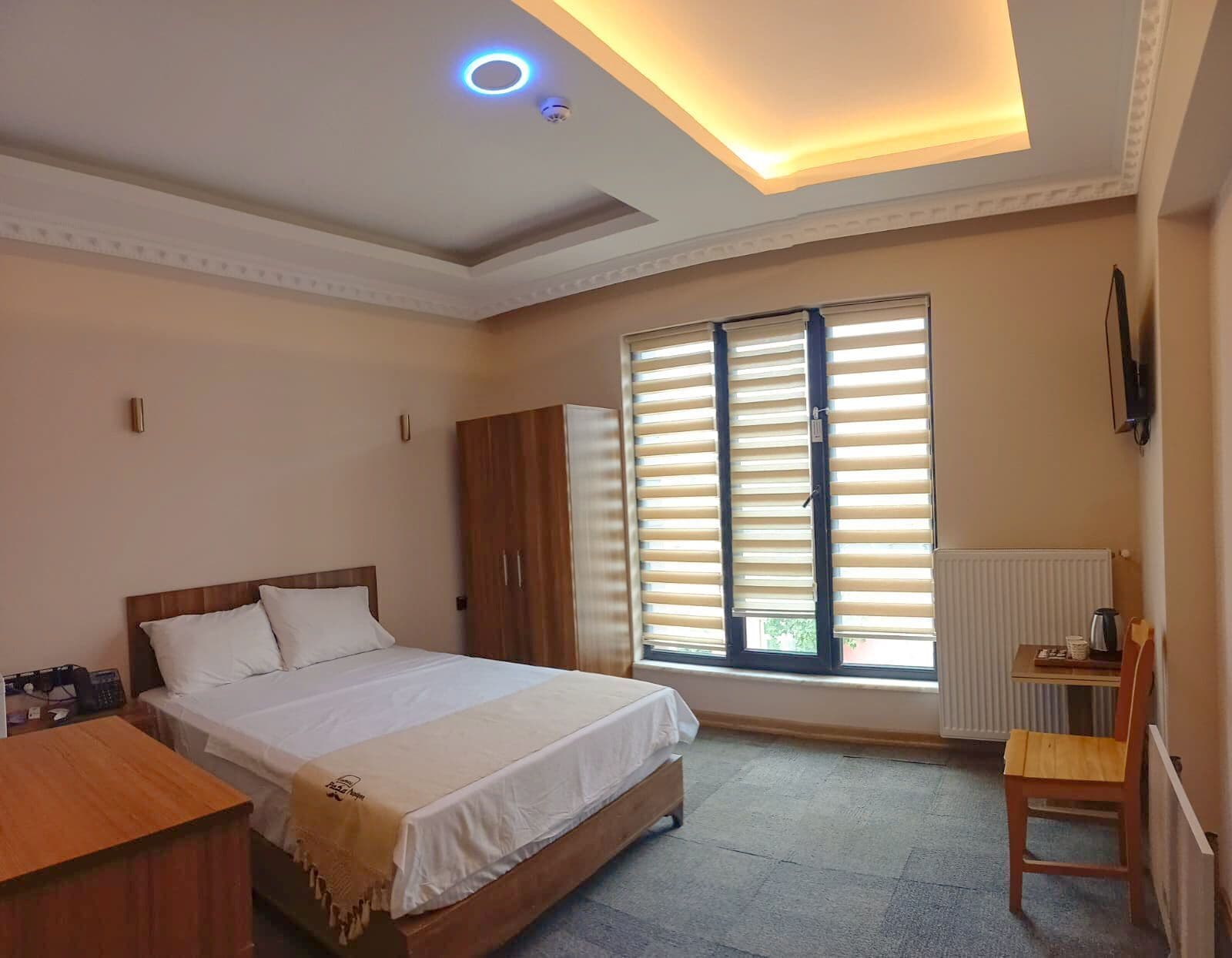 A bedroom with a bed, wardrobe, and a desk with a chair.