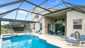 A covered swimming pool with lounge chairs and a patio area.