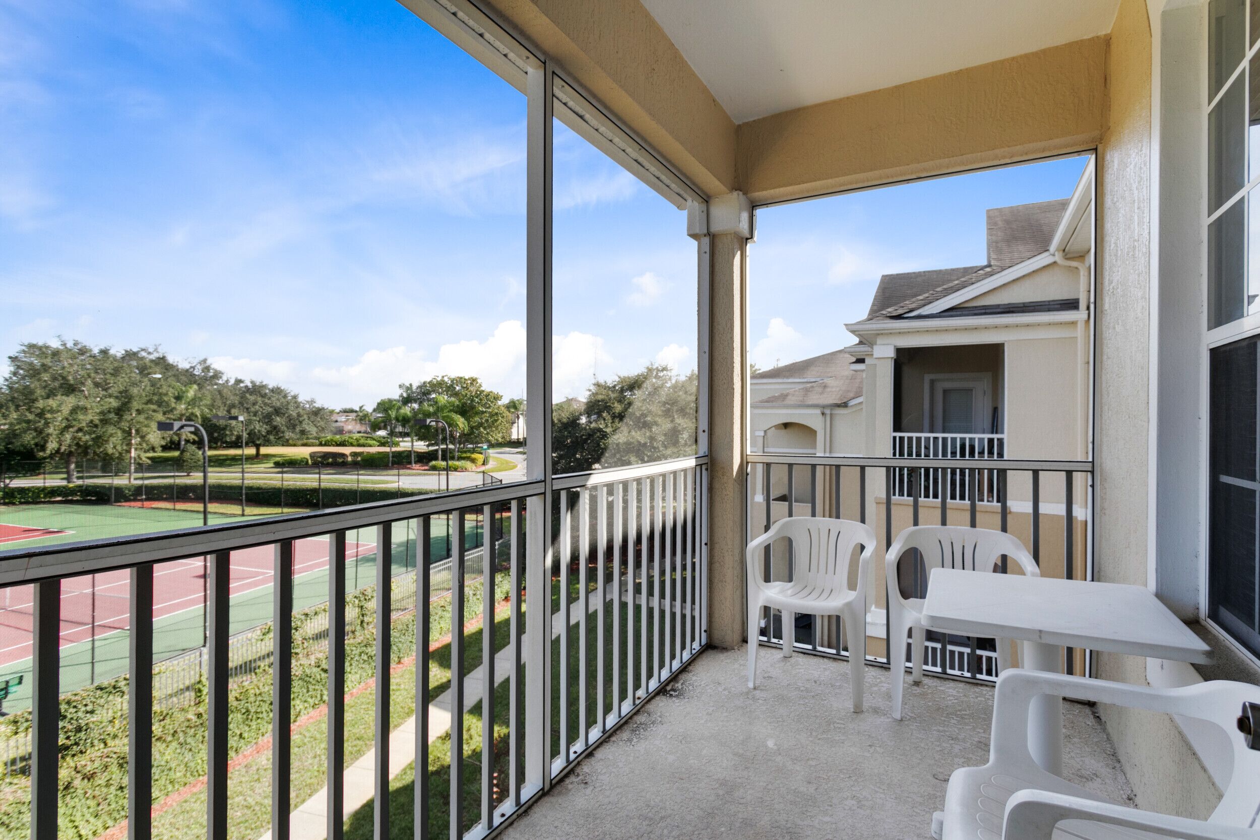A balcony with a view of a tennis court and surrounding greenery.