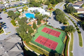 Vista aérea de una zona residencial con piscina, canchas de tenis y aparcamiento.