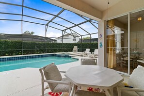 Ein überdachter Außenbereich mit Pool, Sitzgelegenheiten und einem Tisch.