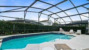 Piscina externa coberta com espreguiçadeiras e uma pequena mesa.