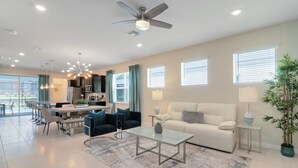 A spacious living room with a sofa, coffee table, and dining area. - Last Minute Disney Getaway! Luxury Villa with Private Pool & Game Room. Book Now! #49491 (Orlando)
