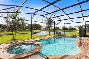 Una piscina con idromassaggio, circondata da un portico coperto con vista su un lago e delle case.