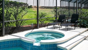 Un jacuzzi con borde de azulejos, rodeado por un porche cubierto con sillas.
