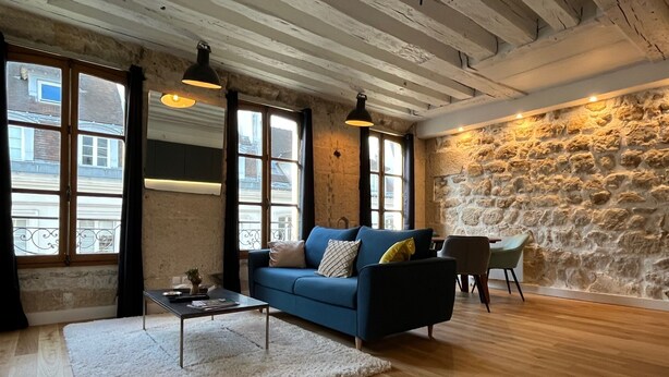 Ein Wohnzimmer mit einem blauen Sofa, einem Couchtisch und einer Steinwand.