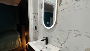 Ein Badezimmer mit weißem Waschbecken, schwarzem Schrank und einem Spiegel mit Beleuchtung.