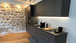 Eine moderne Küche mit dunklen Schränken, einer Wand aus Naturstein und Holzboden.