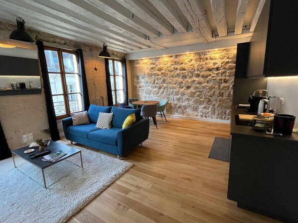 Un espai de vida modern amb un sofà blau, una taula de centre i una paret de pedra.