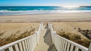A wooden boardwalk leading to a beach with a pier in the background. - Big Blue -Mini-Resort, Movie Theater, Pools, Hot Tub, Beach Front, Sleeps 28! (Surf City)