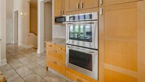A kitchen with wooden cabinets, a stainless steel oven, and a microwave. - Big Blue -Mini-Resort, Movie Theater, Pools, Hot Tub, Beach Front, Sleeps 28! (Surf City)