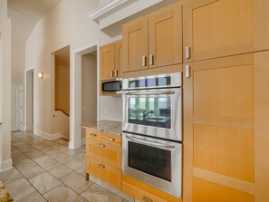Una cocina con armarios de madera, un horno de acero inoxidable y un microondas.