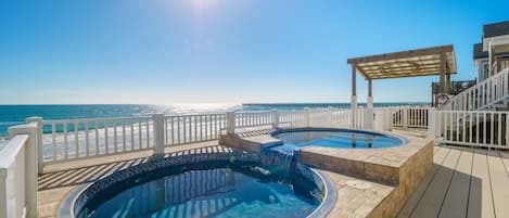 Ein Poolbereich mit zwei Whirlpools und einer Pergola mit Blick auf einen Strand.