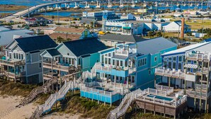 A coastal resort with multiple-story buildings featuring balconies and a beach access walkway. - Big Blue -Mini-Resort, Movie Theater, Pools, Hot Tub, Beach Front, Sleeps 28! (Surf City)