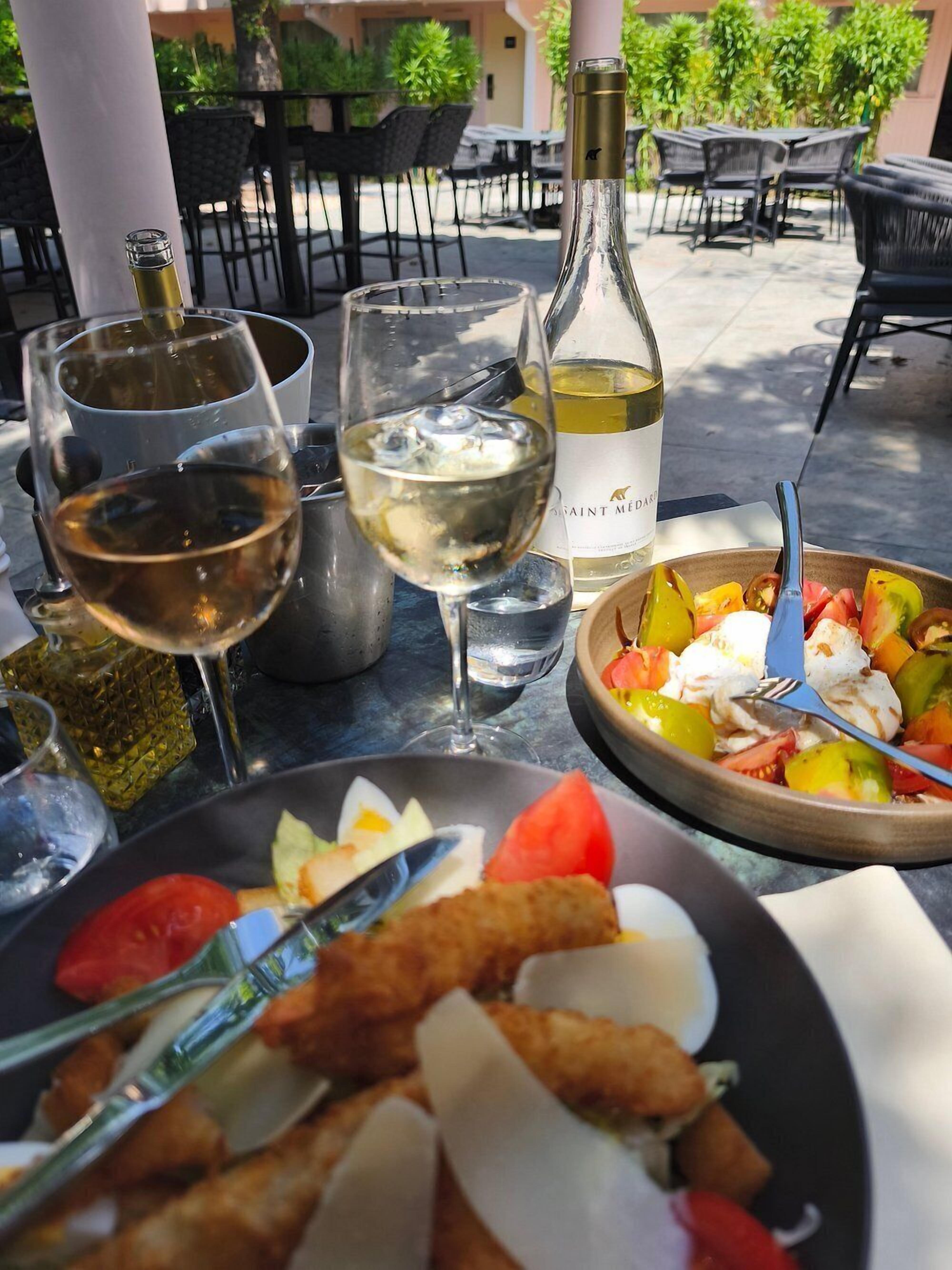 Ein Tisch mit einer Weinflasche, Gläsern und einer Speisenplatte.