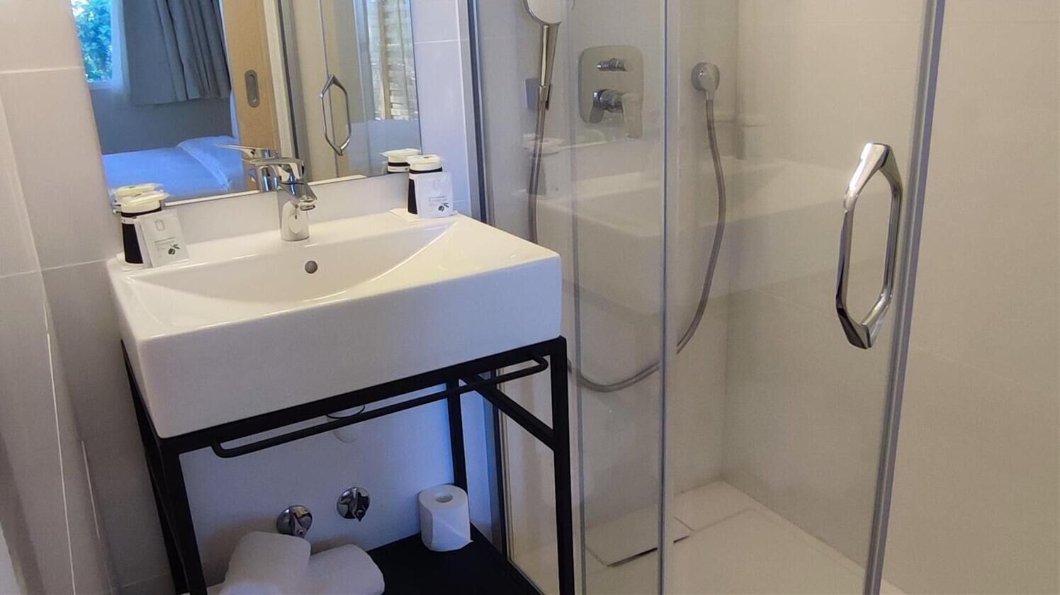 Een moderne badkamer met een wit wastafelmeubel, spiegel en een douchecabine met glazen wanden.