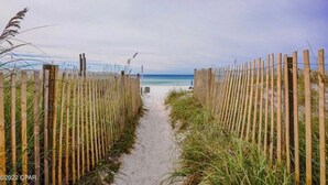 A sandy beach path leading to the ocean, flanked by wooden fences and grass. - Family-friendly oceanfront escape w/ views steps from private beach (Panama City Beach)