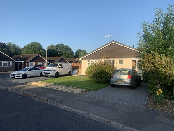 A residential street with houses, parked cars, and a clear sky.