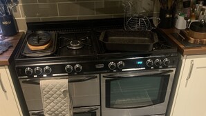 Une cuisine équipée d’une cuisinière, d’un four et d’un sol carrelé.