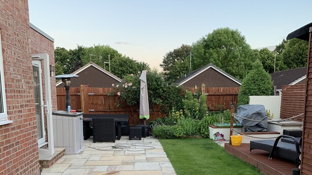 Un jardin bien entretenu avec un espace patio, du mobilier d’extérieur et une pelouse.