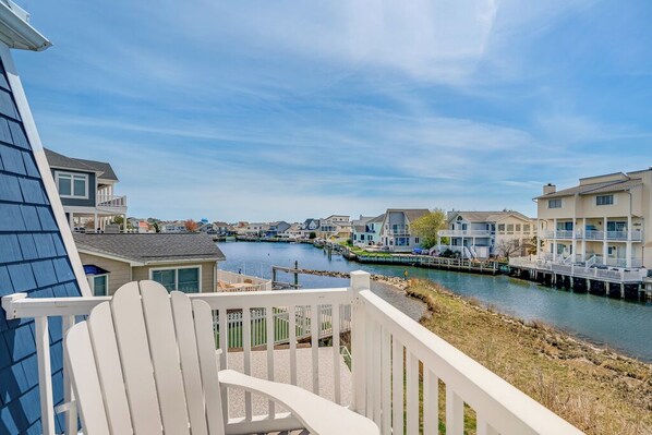A waterfront property with a view of a canal, a wooden deck, and a white railing.