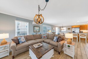 A living room with a sectional sofa, a coffee table, and a dining area with a white table and chairs.