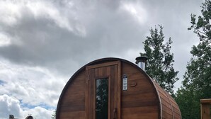 Una struttura a forma di botte in legno con una porta, un estintore e una piccola piattaforma.