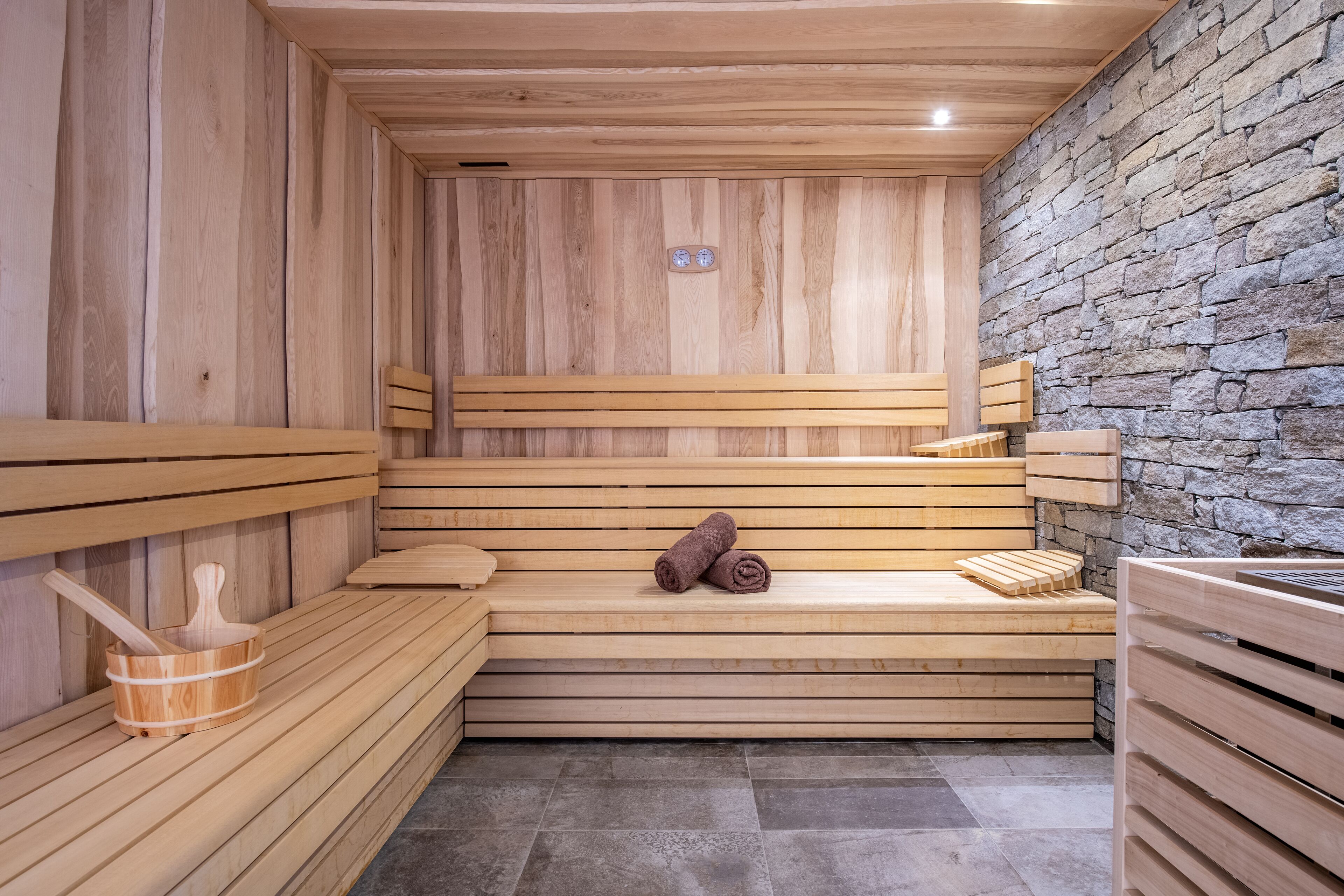 A sauna with wooden benches and a stone wall.