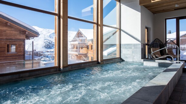 A spa area with a hot tub, large windows, and a view of snowy mountains. - CGH Résidence & Spa White Pearl Lodge (La Plagne-Tarentaise)