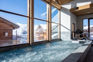 A spa area with a hot tub, large windows, and a view of snowy mountains. - CGH Résidence & Spa White Pearl Lodge (La Plagne-Tarentaise)