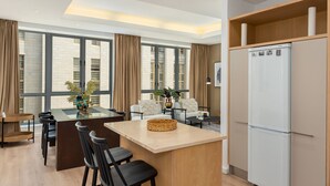 A modern kitchen with a central island, bar stools, a refrigerator, and large windows with curtains. - Sleek Designer Apartment in the heart of Cape Town (Cape Town)