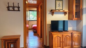 Un mueble de madera con un televisor, una mesita y un estante con un cuadro enmarcado.