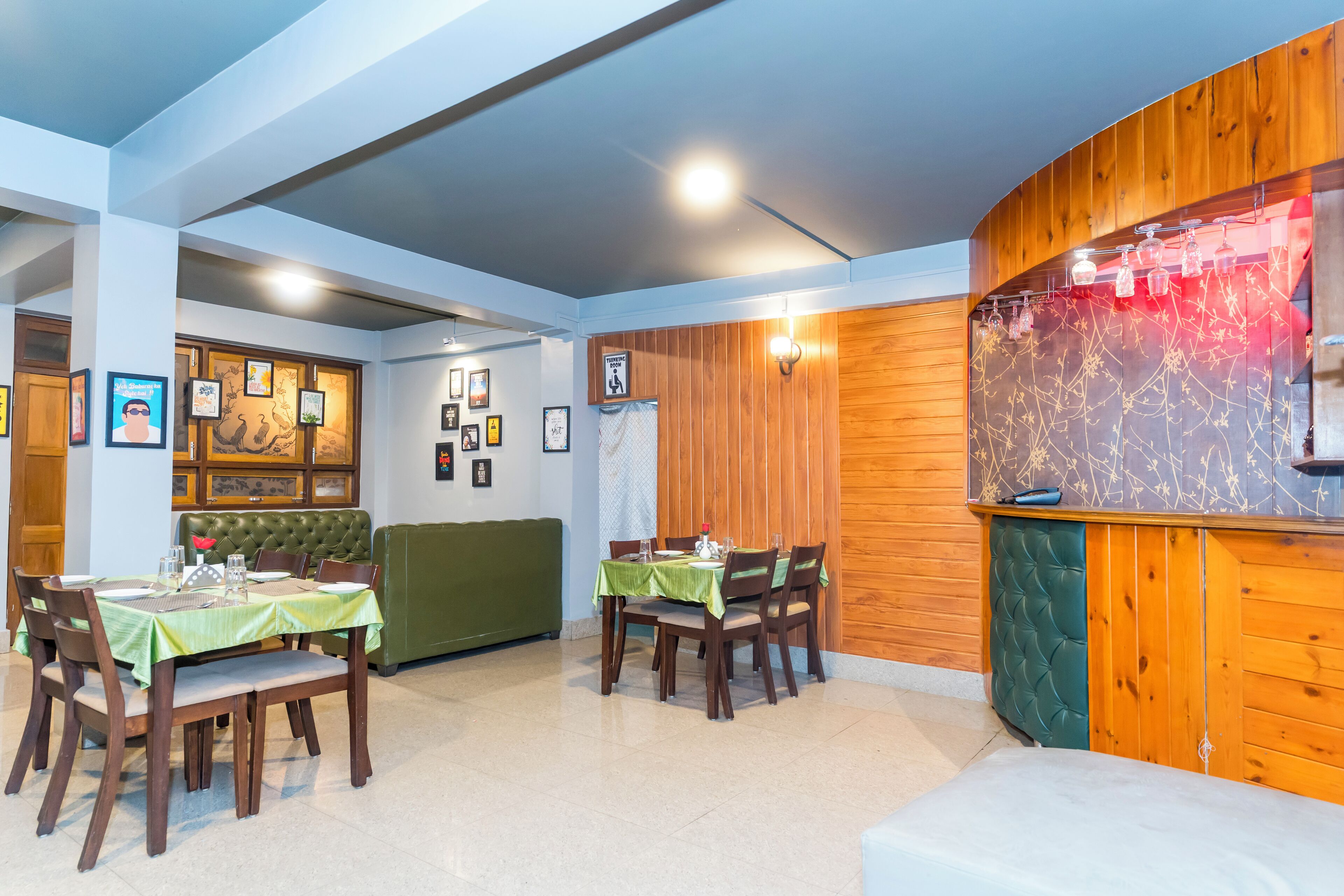 A restaurant with wooden paneling, green cushioned seating, and framed pictures on the walls.