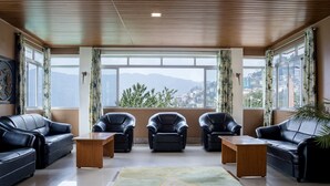 Una sala de estar moderna con sofás de cuero, una mesa de centro de madera y vistas a montañas a través de amplios ventanales.