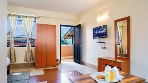 Habitación de hotel con un escritorio de madera, televisión, espejo y vista al exterior.