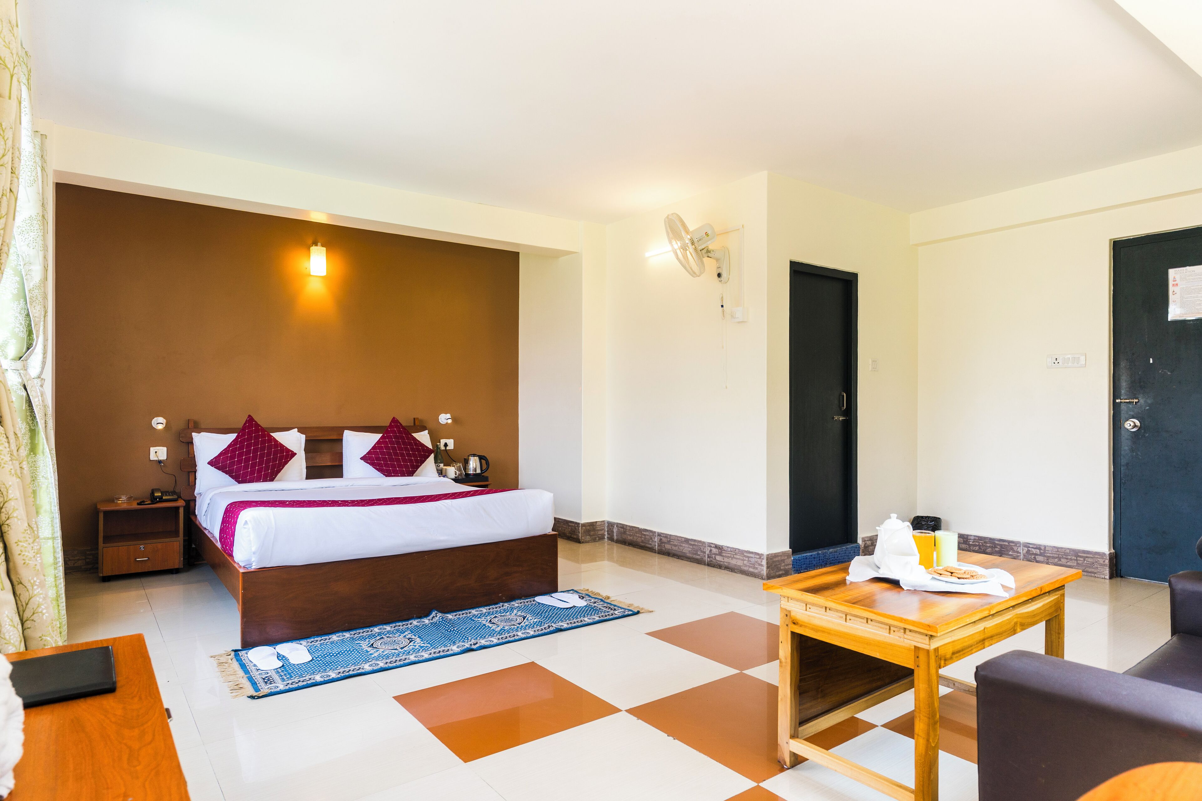 Ein Hotelzimmer mit Bett, Nachttisch und einem kleinen Tisch mit Frühstücksangeboten.