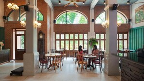 Un amplio comedor con paredes de ladrillo, ventanas grandes y mesas y sillas de madera.