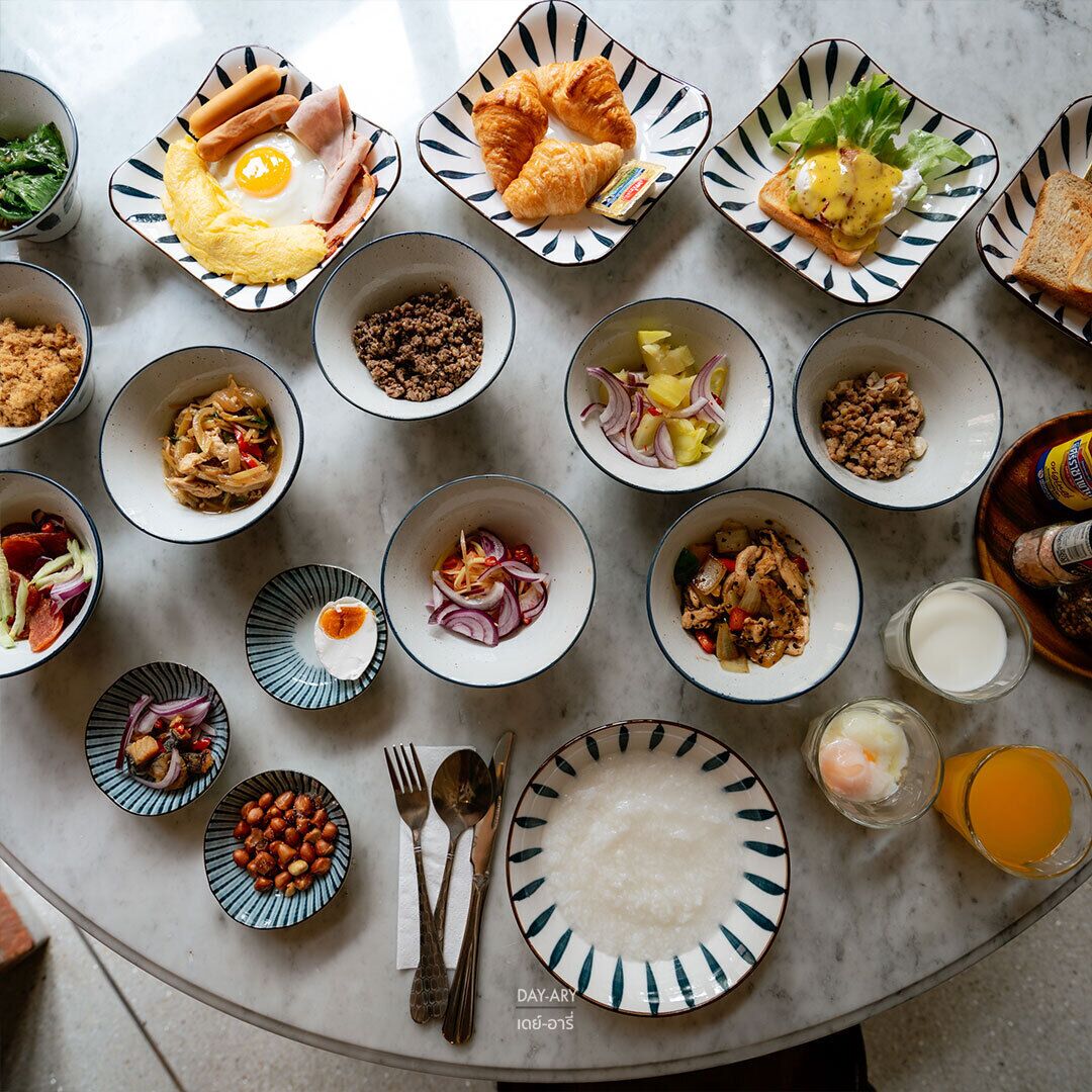 A variety of breakfast dishes arranged on a round table with plates, bowls, and cutlery.
