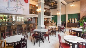 Un restaurante espacioso con varias mesas y sillas, una zona de bar con botellas, y un mapa grande en la pared.
